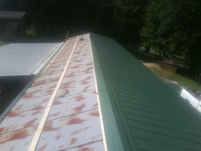Old rusted panels beside newly installed green metal roofing — Wind Damage Roof Repair by Roofing Brothers in Mount Orab