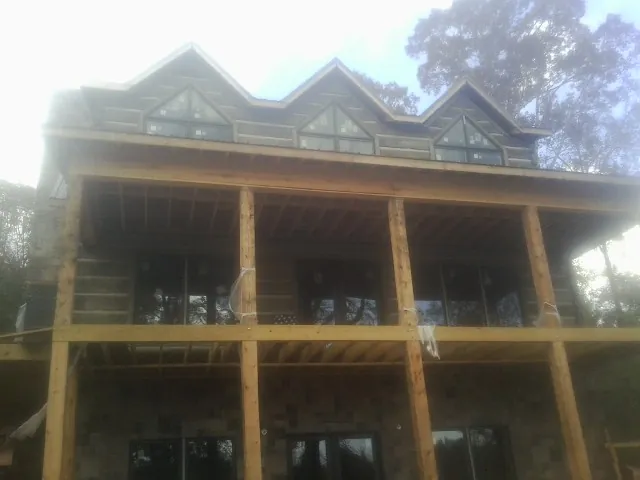 Dormers and porch framing on a large log home under construction — Roof Coating work by our crew in Mount Orab