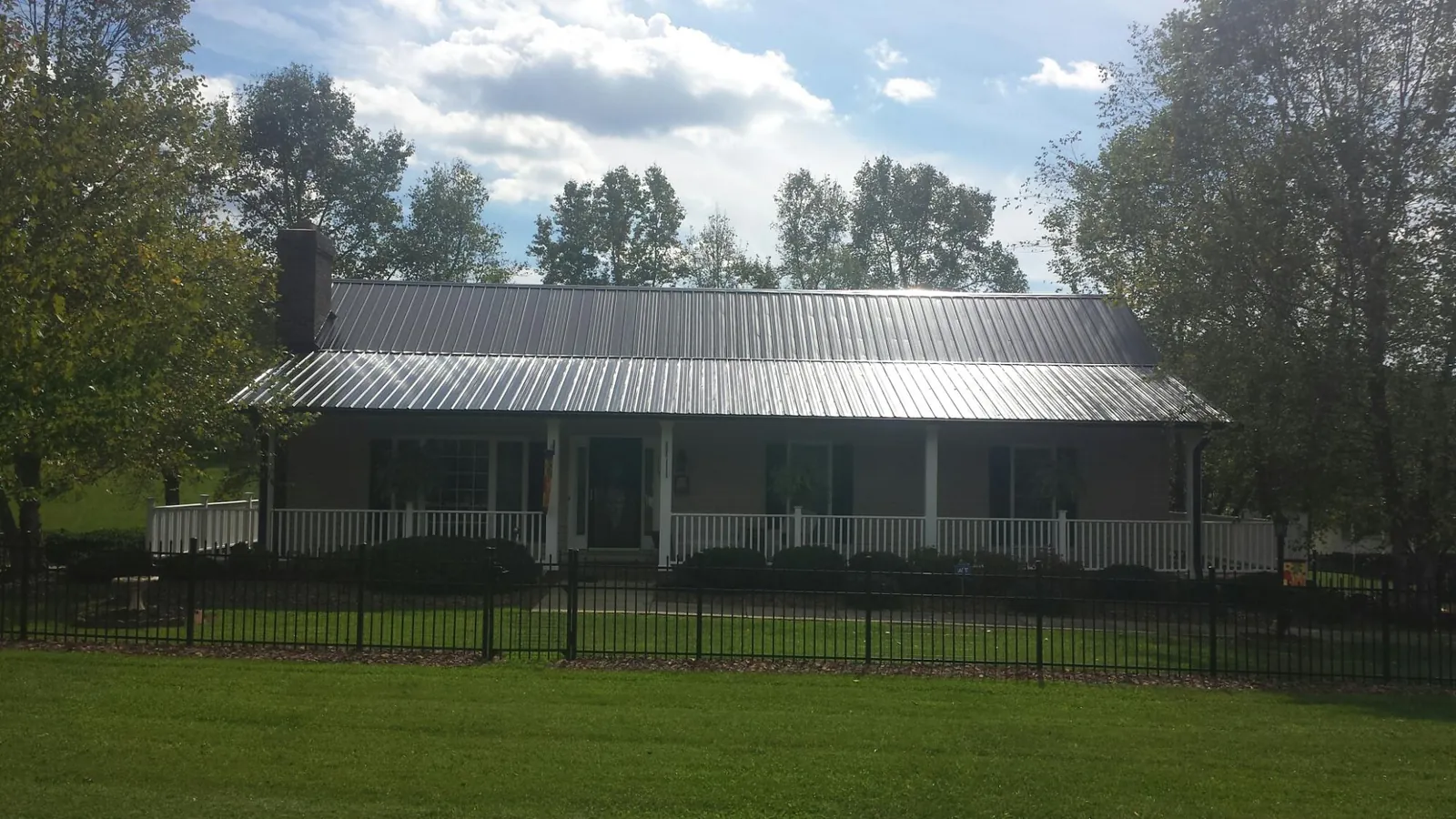 Gray metal roof on a brick ranch with a full width front porch — Gutter Guard Installation work by our crew in Mount Orab