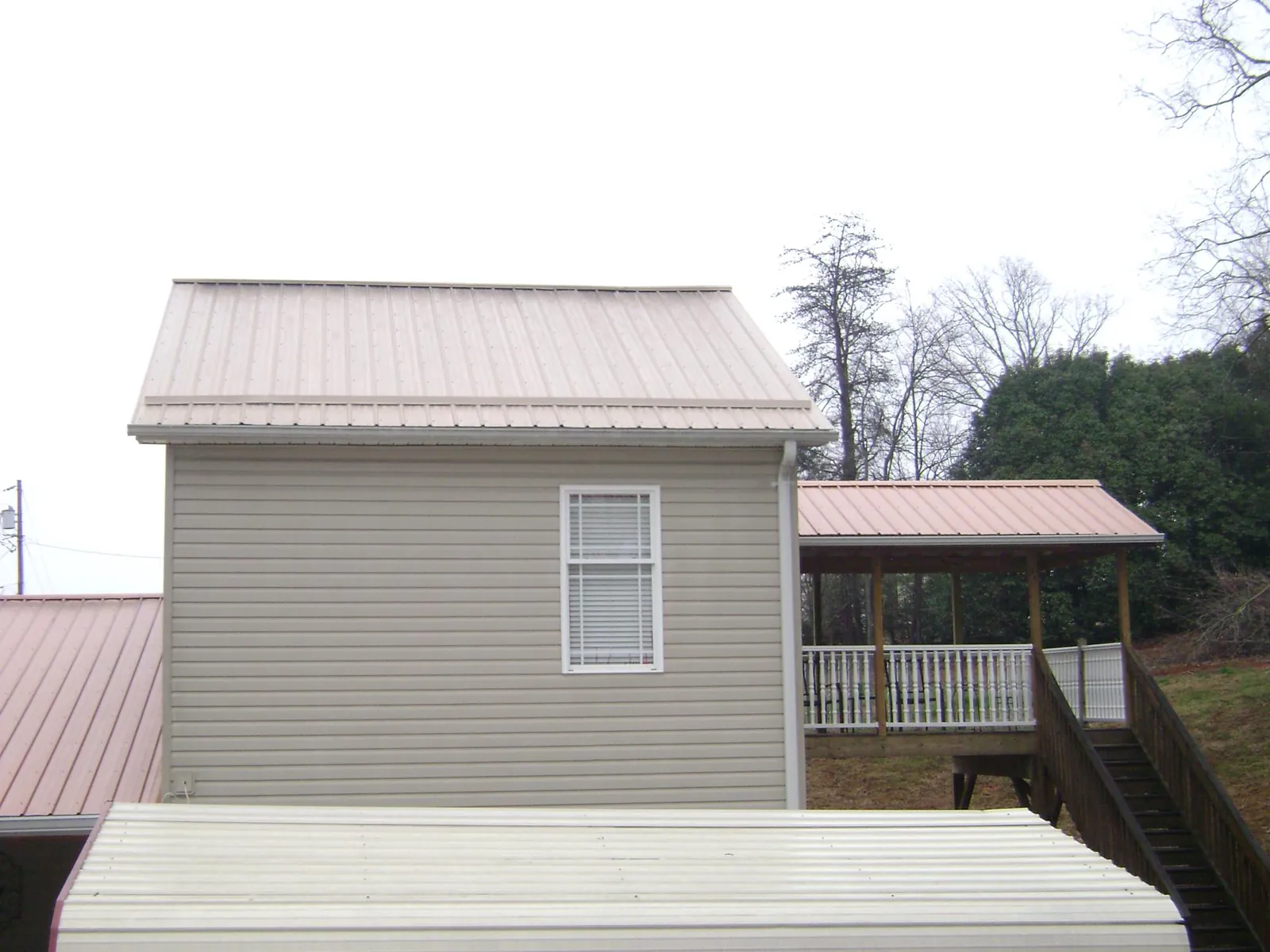 Tan metal roofs on a two story addition and attached porch, from a Roof Replacement job in Mount Orab