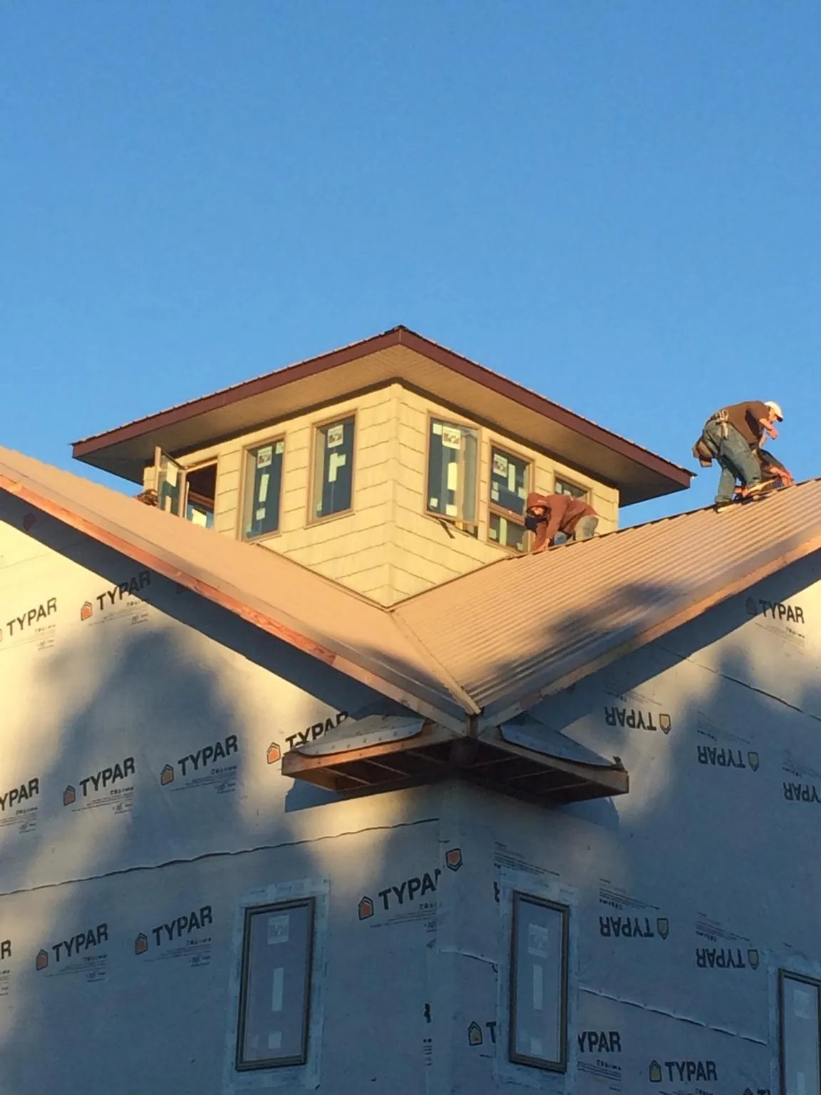 Roofers working around a rooftop cupola on a new metal roof at sunset — Roof Waterproofing in Mount Orab by Roofing Brothers